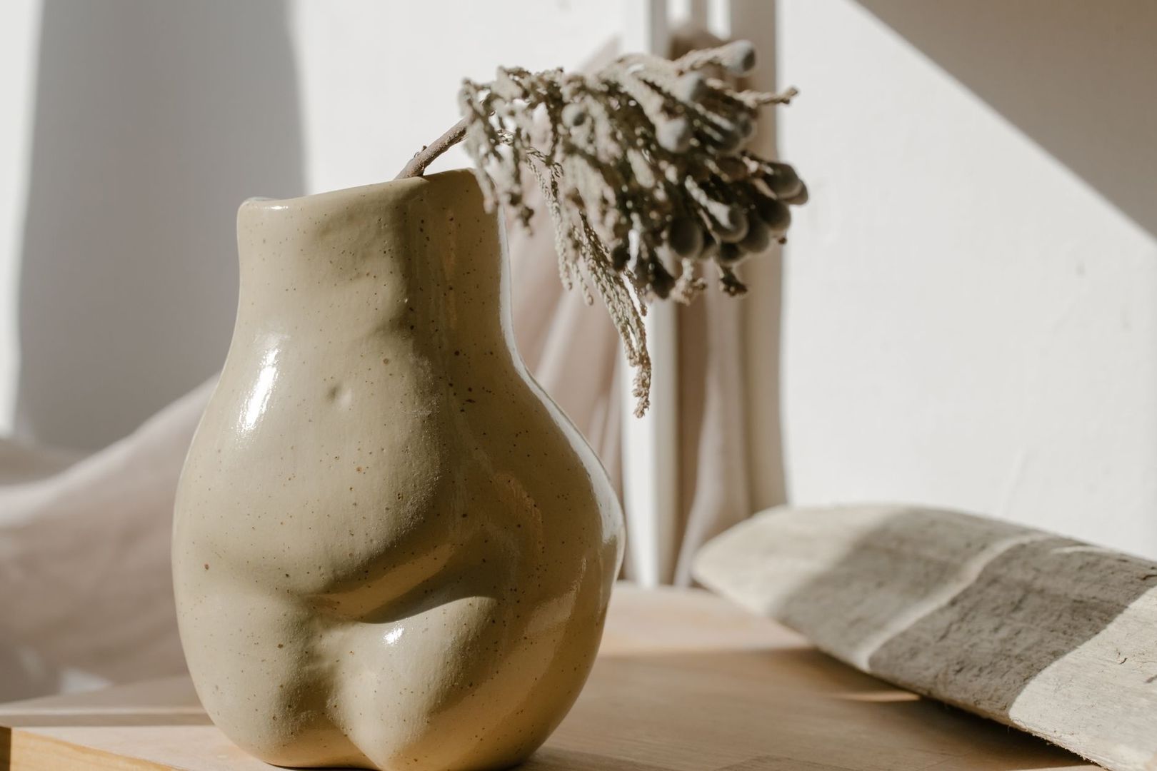 Geglazuurde keramieken vaas met gedroogde bloemen op een houten tafel